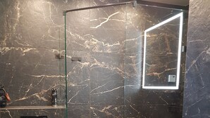 Et moderne badeværelse med en bruseniche i glas, toilet og håndvask.