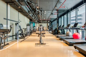 Een sportschool met loopbanden, fitnessapparatuur en grote ramen.