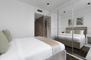 Een moderne hotelkamer met een groot bed, een spiegel en een klein nachtkastje.