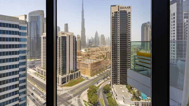 A high-rise building with a prominent 'EMAR' sign, surrounded by other modern buildings and a busy street. - Sky-high Panoramic Apt w Iconic Burj Khalifa Vws (Dubai)
