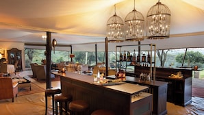 Un área de bar con carpas, taburetes de madera, una barra y candelabros colgantes.