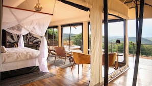Un dormitorio con cama a dosel, un balcón con asientos y vistas al exterior.