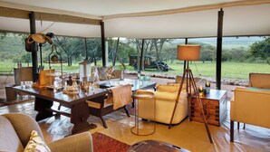Un espacio habitable de concepto abierto con una mesa grande, sofás y vistas al exterior.