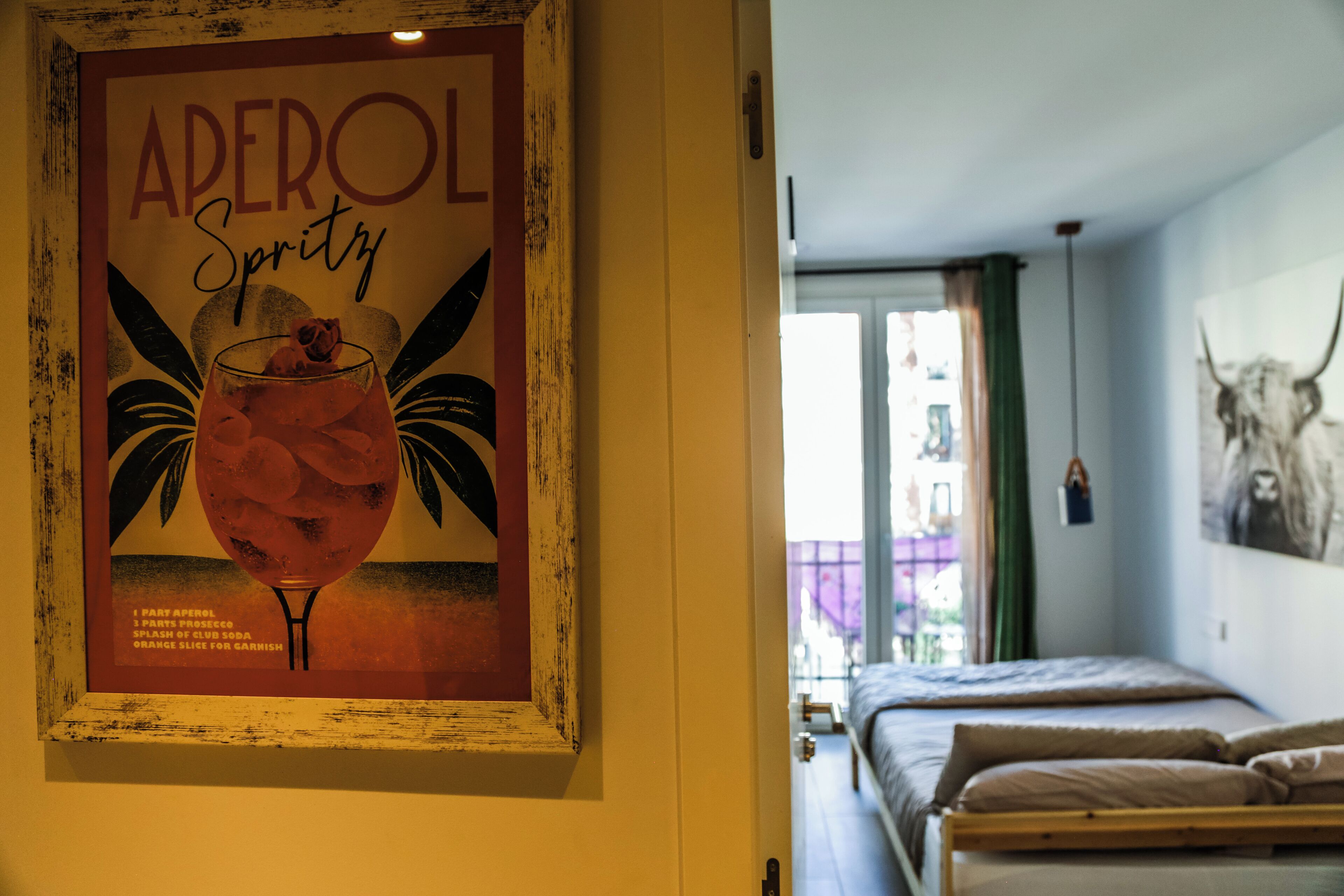 A room with a bed, a framed poster on the wall, and a window with curtains.