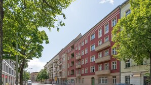 En byggnad med flera våningar, balkonger, en grön dörr och en väl synlig butiksfasad med en skylt.
