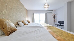 Habitación de hotel con una cama grande, un escritorio y una silla. Hay una ventana con cortinas, una lámpara colgante y un aire acondicionado instalado en la pared.