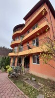 Un edificio de varios pisos con balcones, un sendero de ladrillo y vegetación circundante.