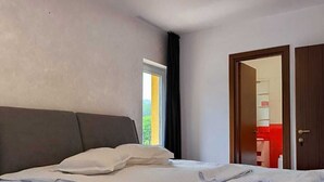 A modern hotel room with a large bed, a window with curtains, and a door leading to a bathroom. - Pensiunea Lucy Sinaia (Sinaia)