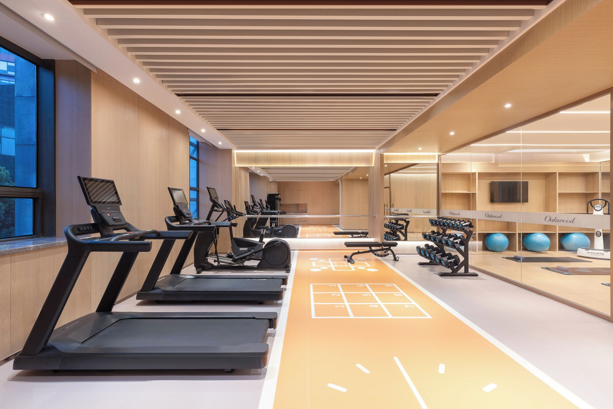 A modern gym with treadmills, exercise bikes, and a mirrored wall.