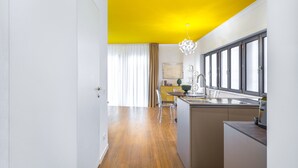 A modern kitchen with a yellow ceiling, wooden flooring, and a large window.