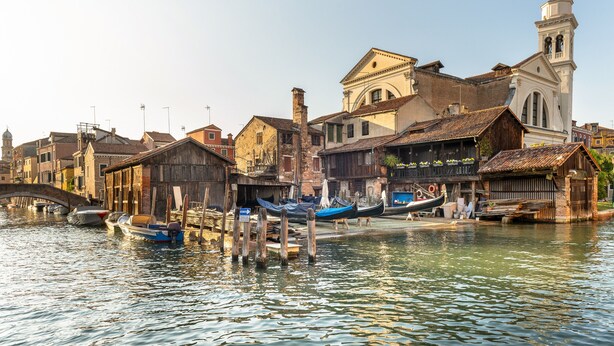 A canal with boats docked, historic buildings, and a bridge. - Domus Carla With Garden R&R (Venecia)