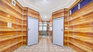 A hallway with wooden panel walls, two white doors, and a patterned floor. - Deluxe Hotel New Time Star (Srinagar)