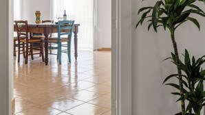Un coin repas avec une table et des chaises, une plante en pot et une vue sur une autre pièce.