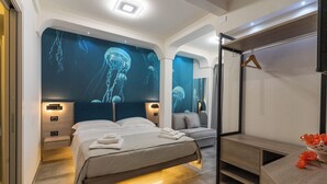 A modern hotel room with a large bed, a sofa, and a desk. - Carizza Rooms (Pozzallo)