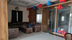 A living room with a sofa, a coffee table, and a glass door with balloons. - Hotel The Castle Inn (Varanasi)