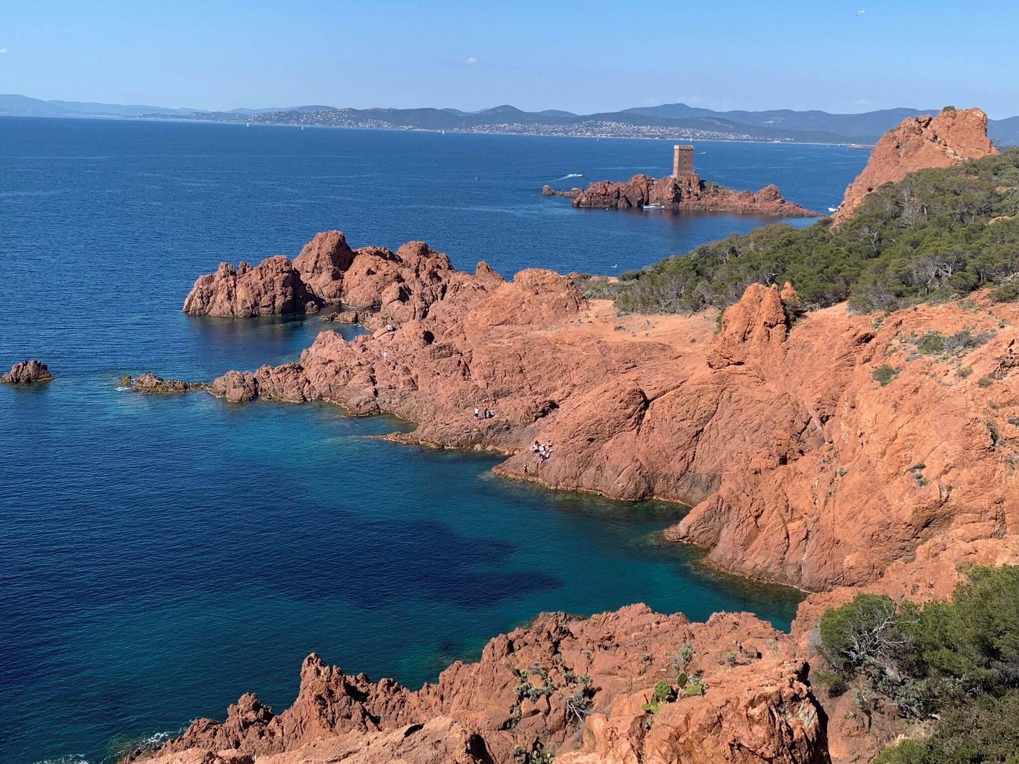 A coastal landscape with rocky formations and a tower on a small island.