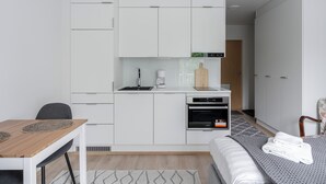 Una habitación moderna y compacta con kitchenette, comedor y cama.