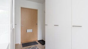 Un pasillo con una puerta de madera, un felpudo negro y una pared blanca.
