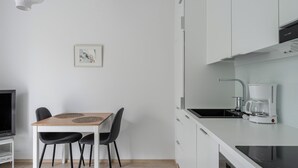 Una cocina moderna con armarios blancos, encimera negra y cafetera.