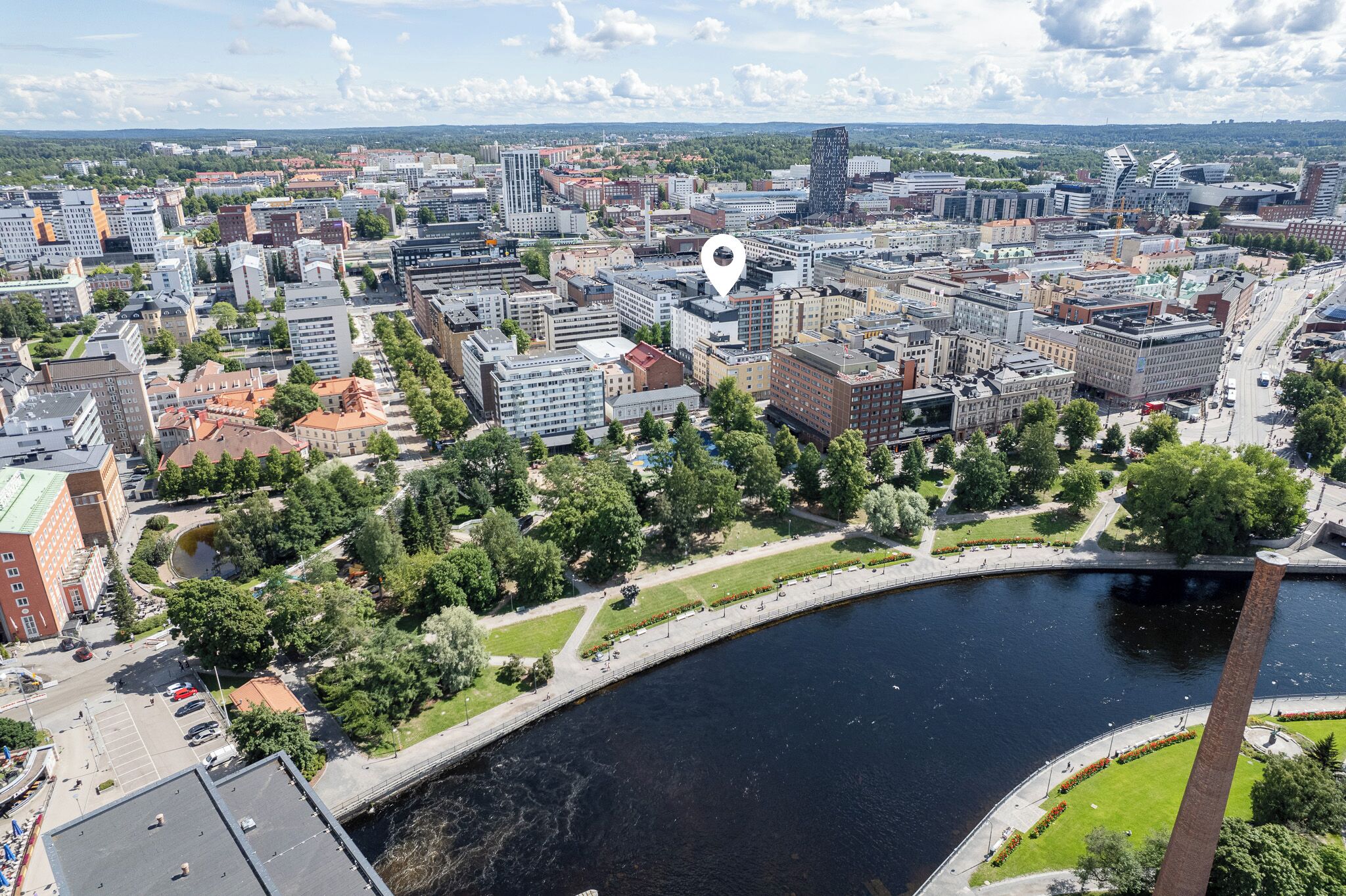 An aerial view of a city with a river, modern buildings, and a park area.
