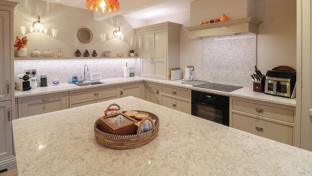 Una cocina moderna con una isla grande, electrodomésticos integrados e iluminación colgante.