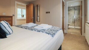 Un dormitorio con cama, mesita de noche, ventana con persianas, una puerta y zona de ducha.