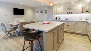 Una cocina moderna con una isla central, taburetes de bar e iluminación colgante.