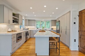 A modern kitchen with a central island, stainless steel appliances, and a large window providing natural light.