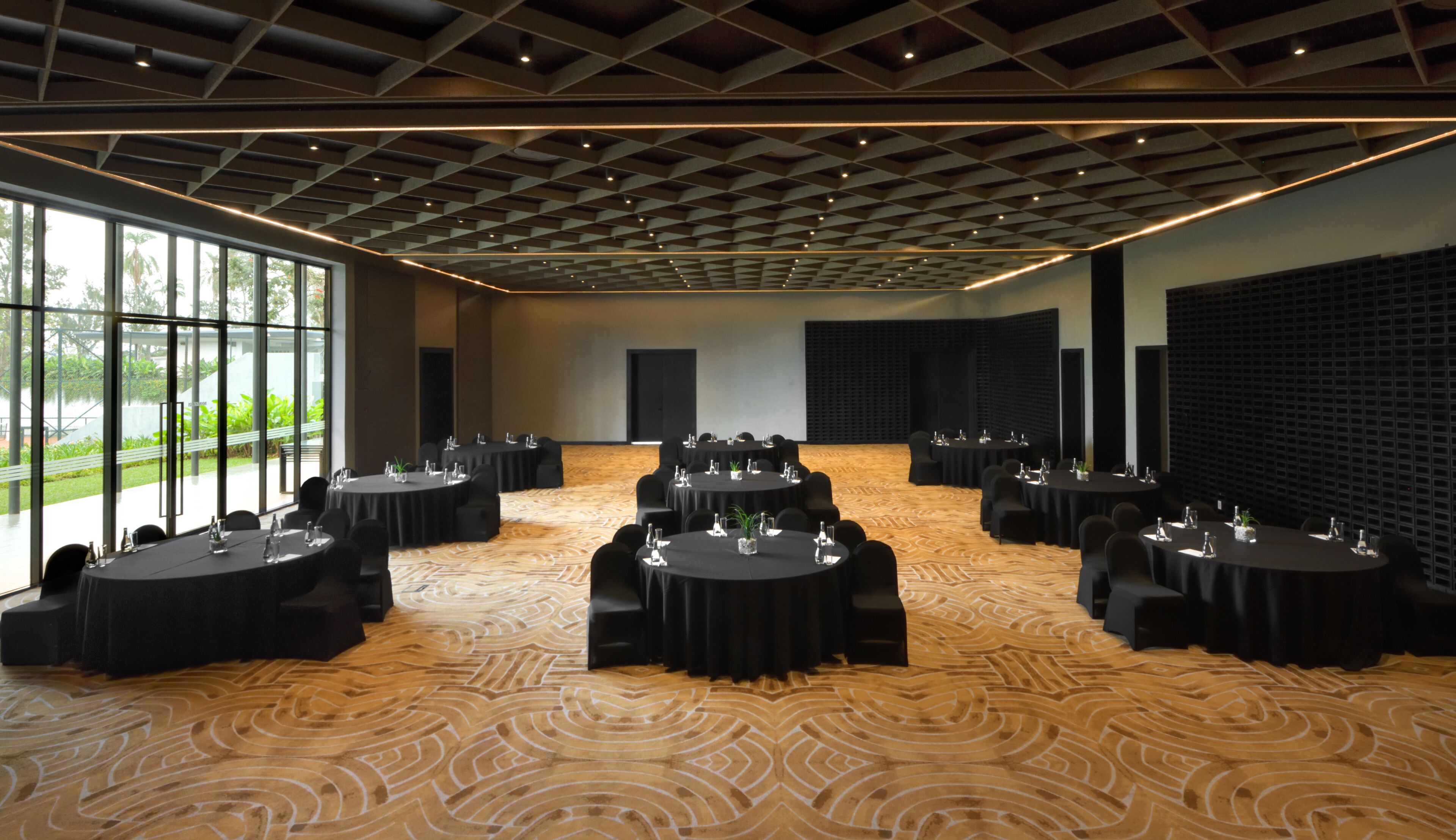 A conference room with round tables, black chairs, and a patterned carpet.
