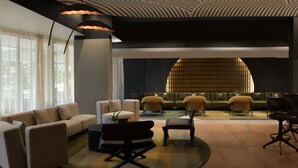 Un lobby moderno con un sofá, sillas, una mesa de centro y un diseño de techo único.