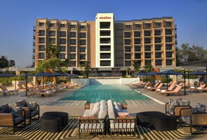 A hotel with a swimming pool, sun loungers, and umbrellas.