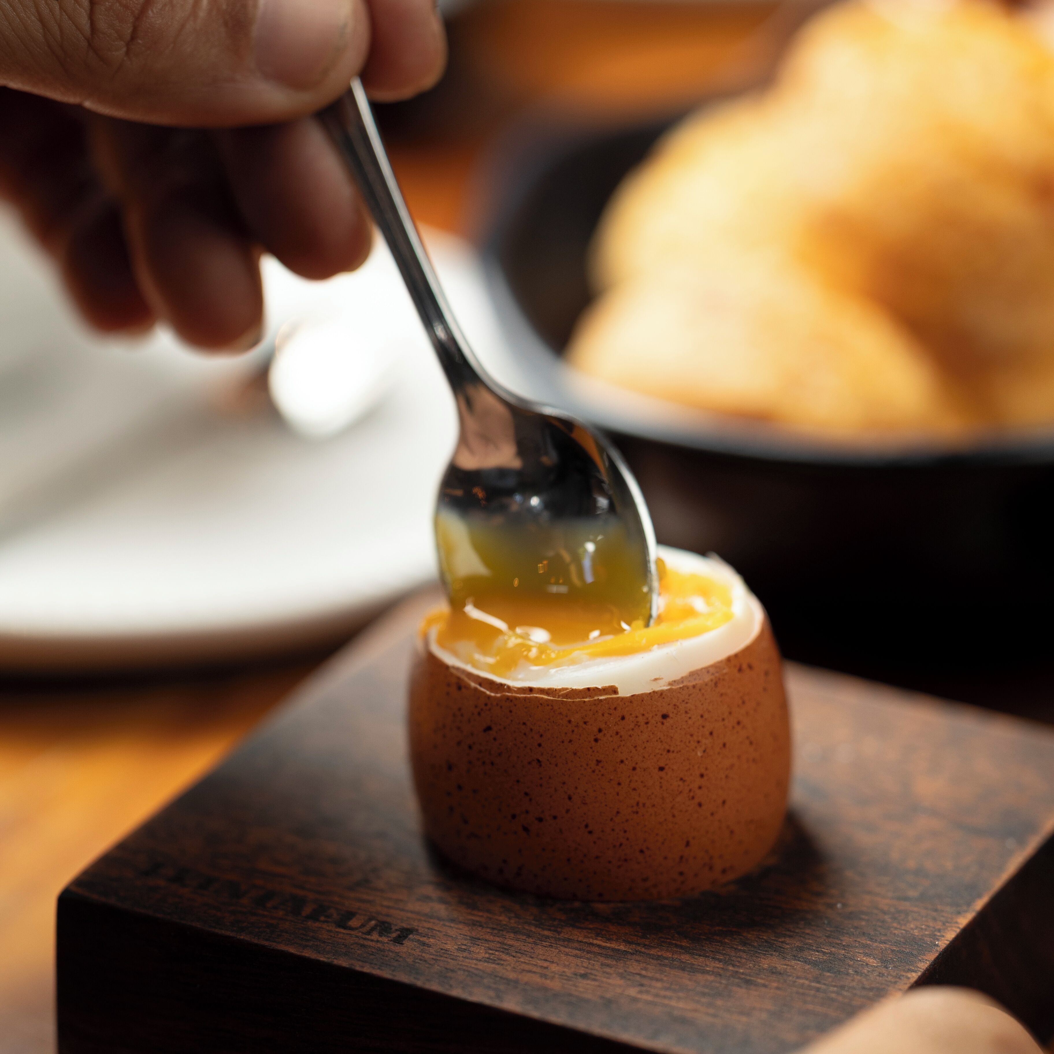 A spoonful of egg yolk on a small, round, brown object.