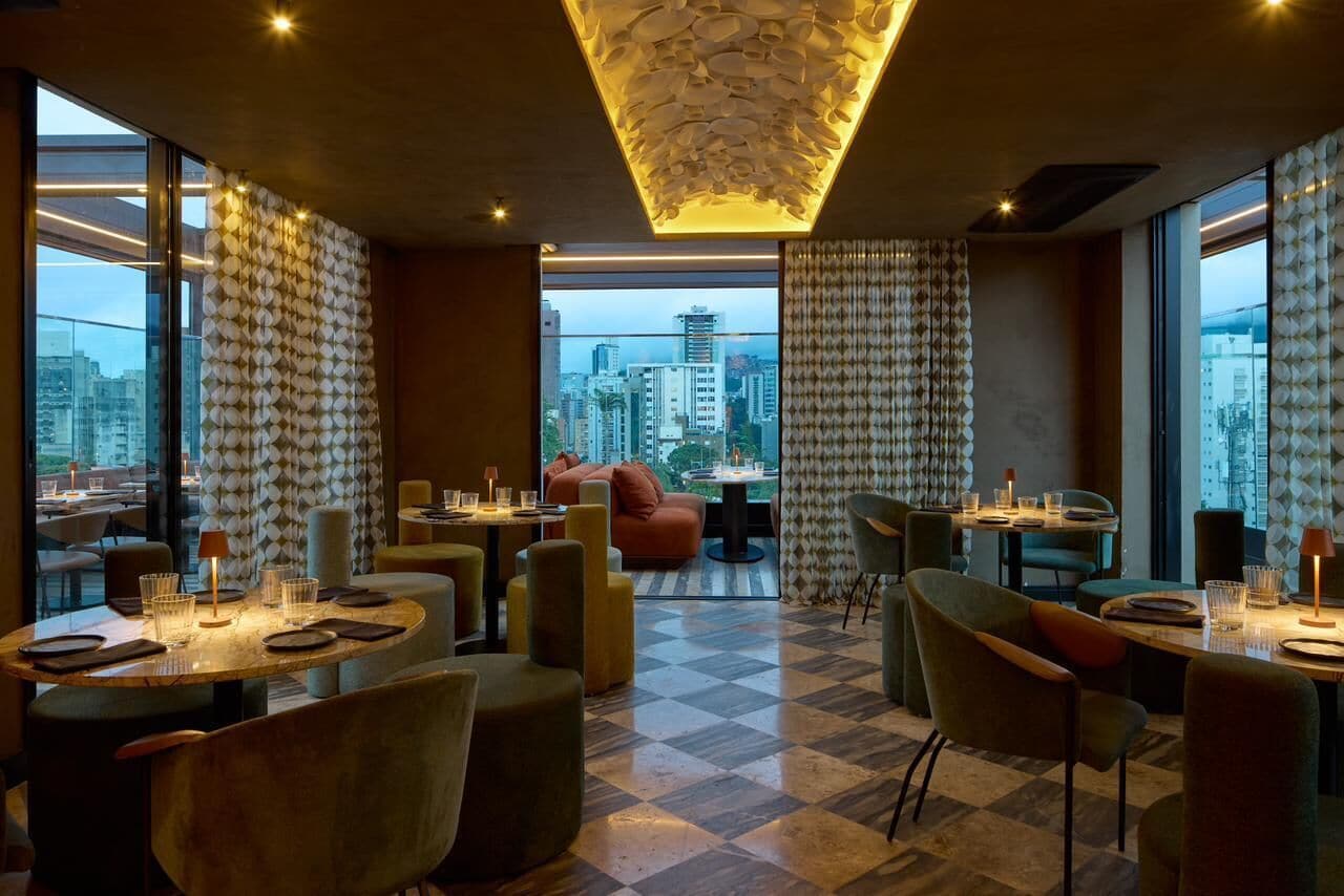 Un espace repas moderne avec un sol à carreaux, des tables rondes et des sièges confortables.