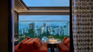 Un salon moderne avec vue sur la ville, comprenant une table ronde et deux canapés.