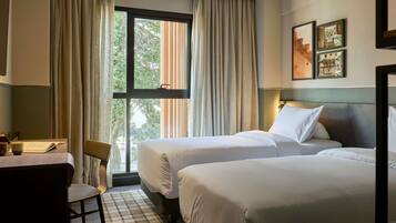 A hotel room with two beds, a desk, and a chair.