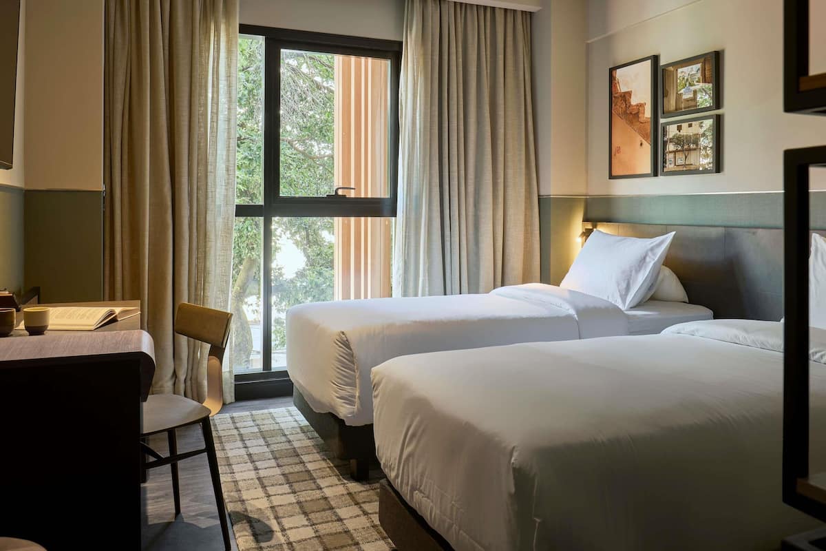 A hotel room with two beds, a desk, and a chair.