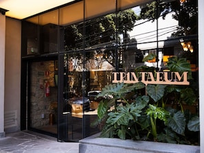 A glass-fronted entrance with a sign reading 'TRINTEUM' and large green plants in front. - Tribe Belo Horizonte Savassi (Belo Horizonte)