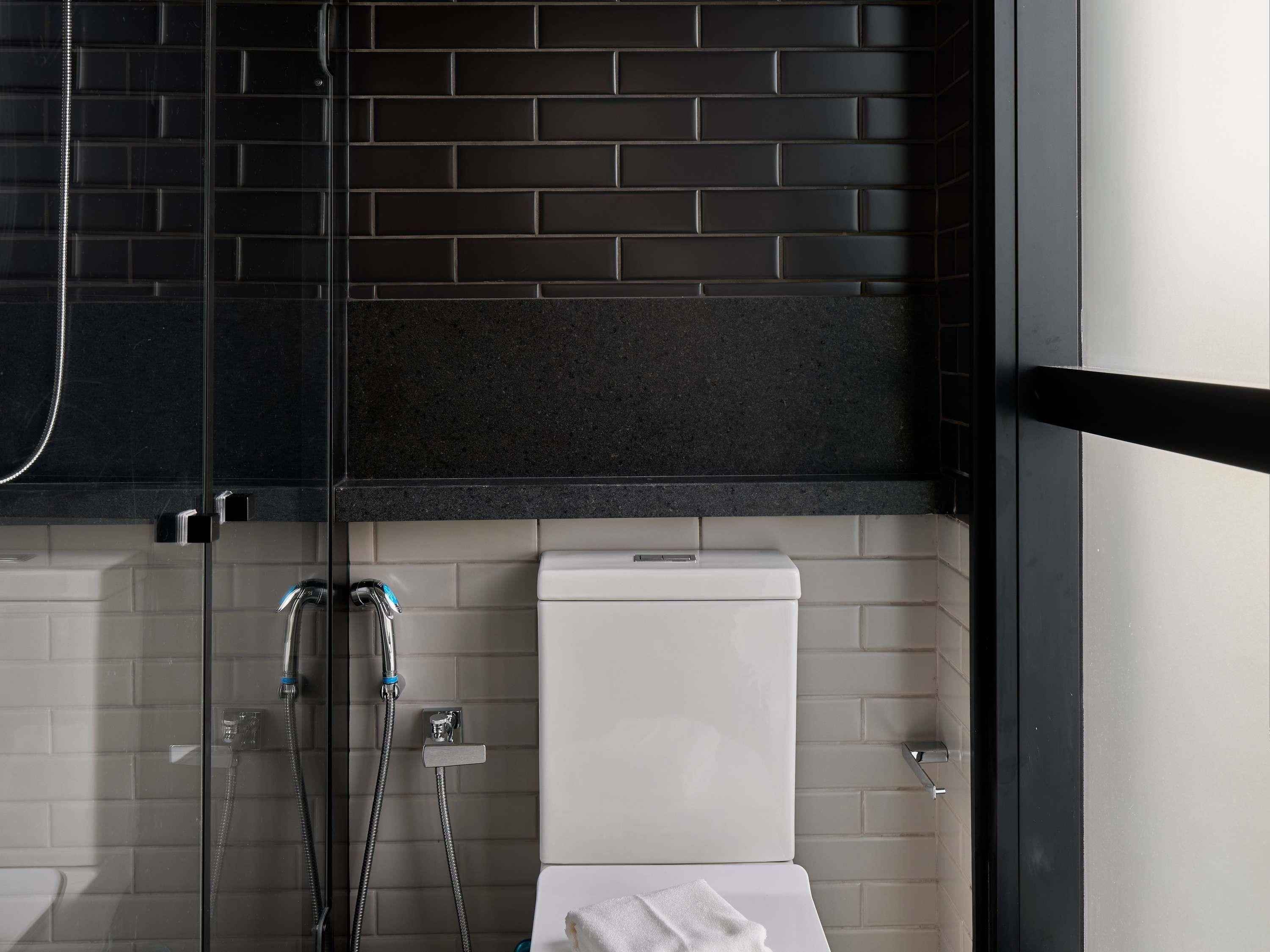 Un bagno moderno con doccia vetrata, un WC bianco e un asciugamano sul pavimento.
