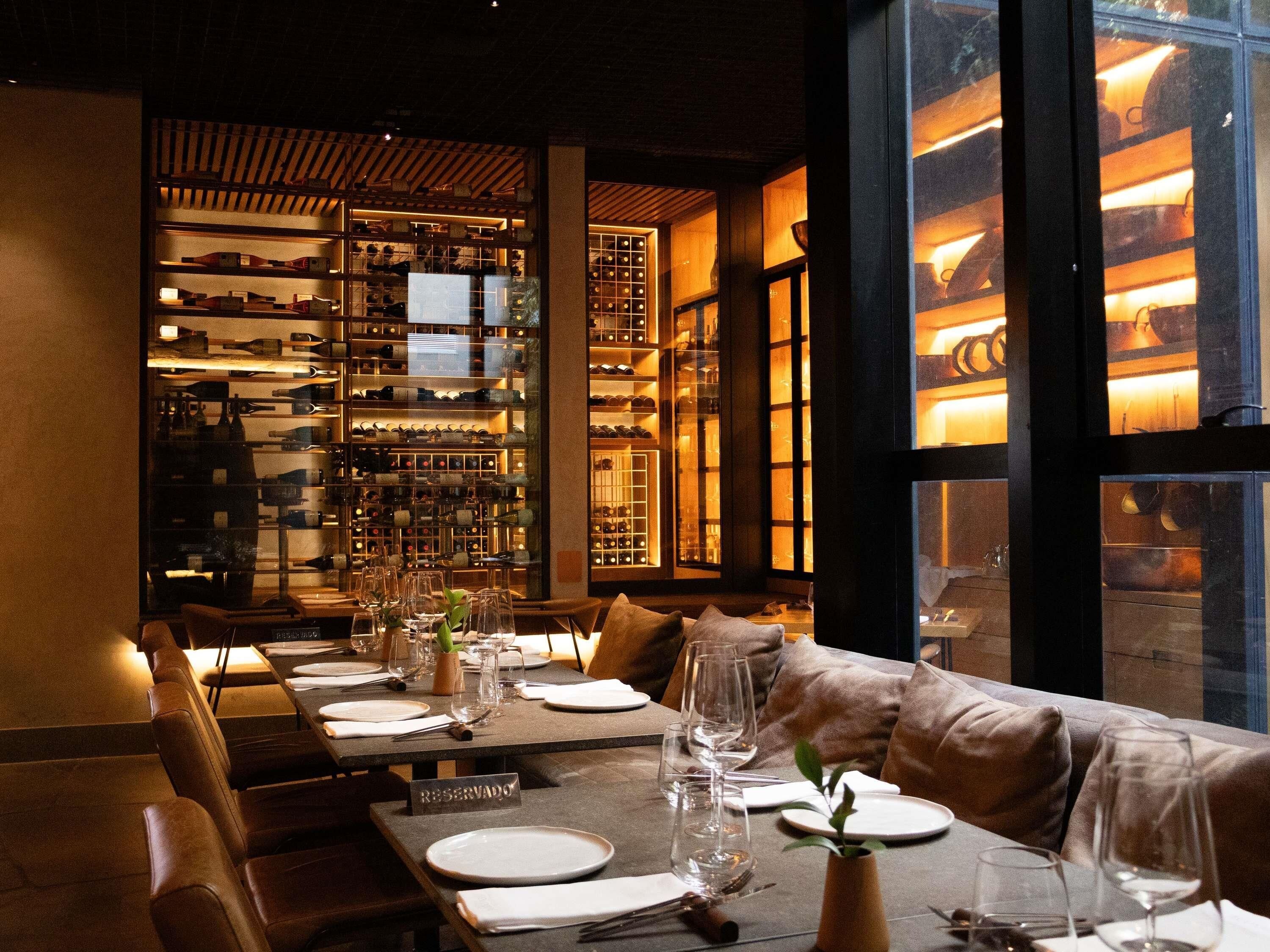 A restaurant with a long table set for a meal, a wine rack in the background, and a reserved sign on the table.