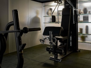 Un gimnasio con una estructura para sentadillas, banco de pesas y discos de pesas.