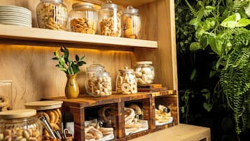 Een houten buffet met glazen potten vol diverse snacks en een bloempot.
