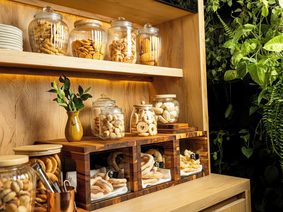 Een houten buffet met glazen potten vol diverse snacks en een bloempot.