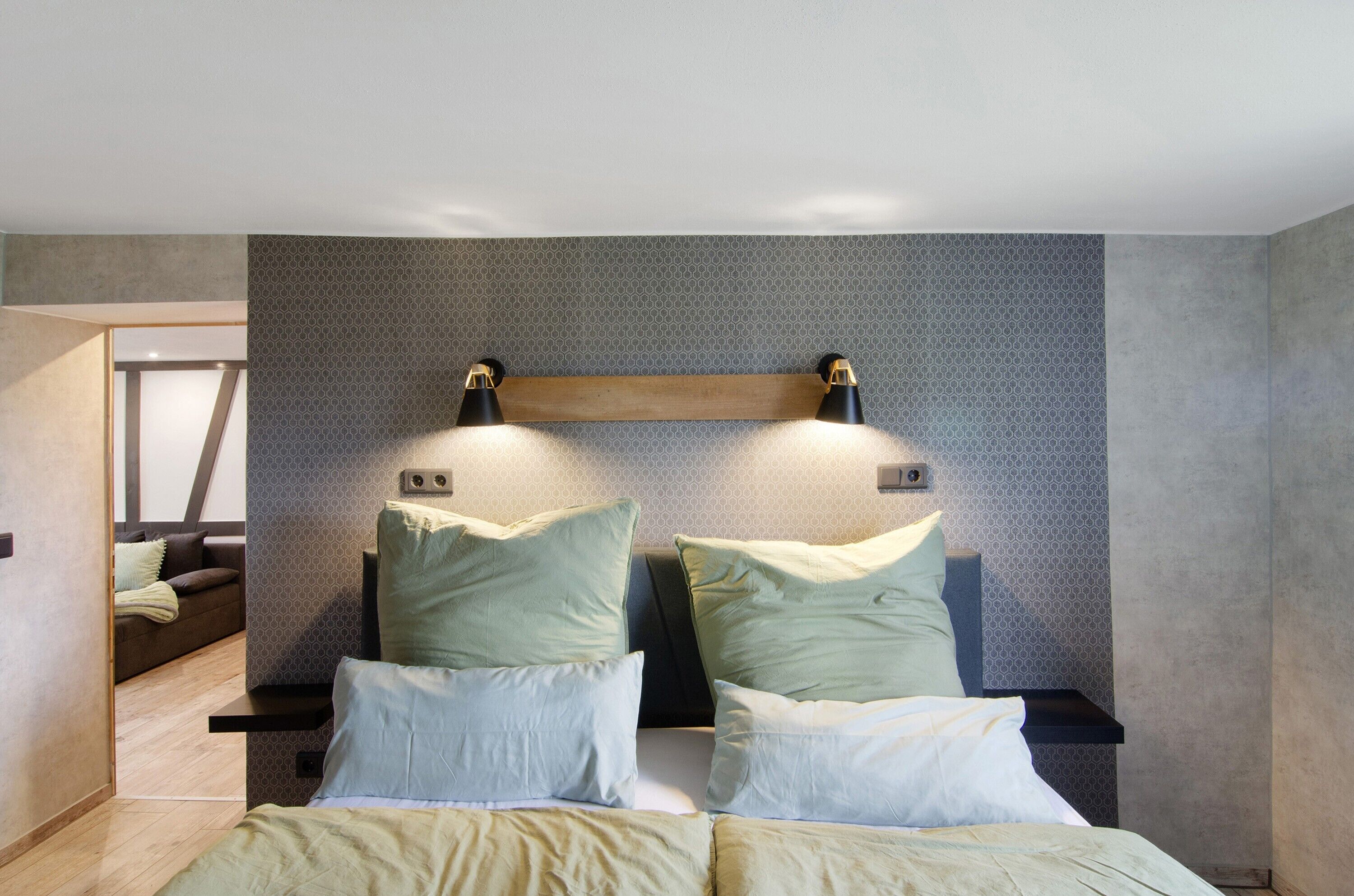 Ein modernes Schlafzimmer mit Bett, Nachttischen und einem Kopfteil mit Wandleuchten.