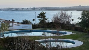 Una piscina de diseño curvo, rodeada de vegetación y con vista a una extensa masa de agua.