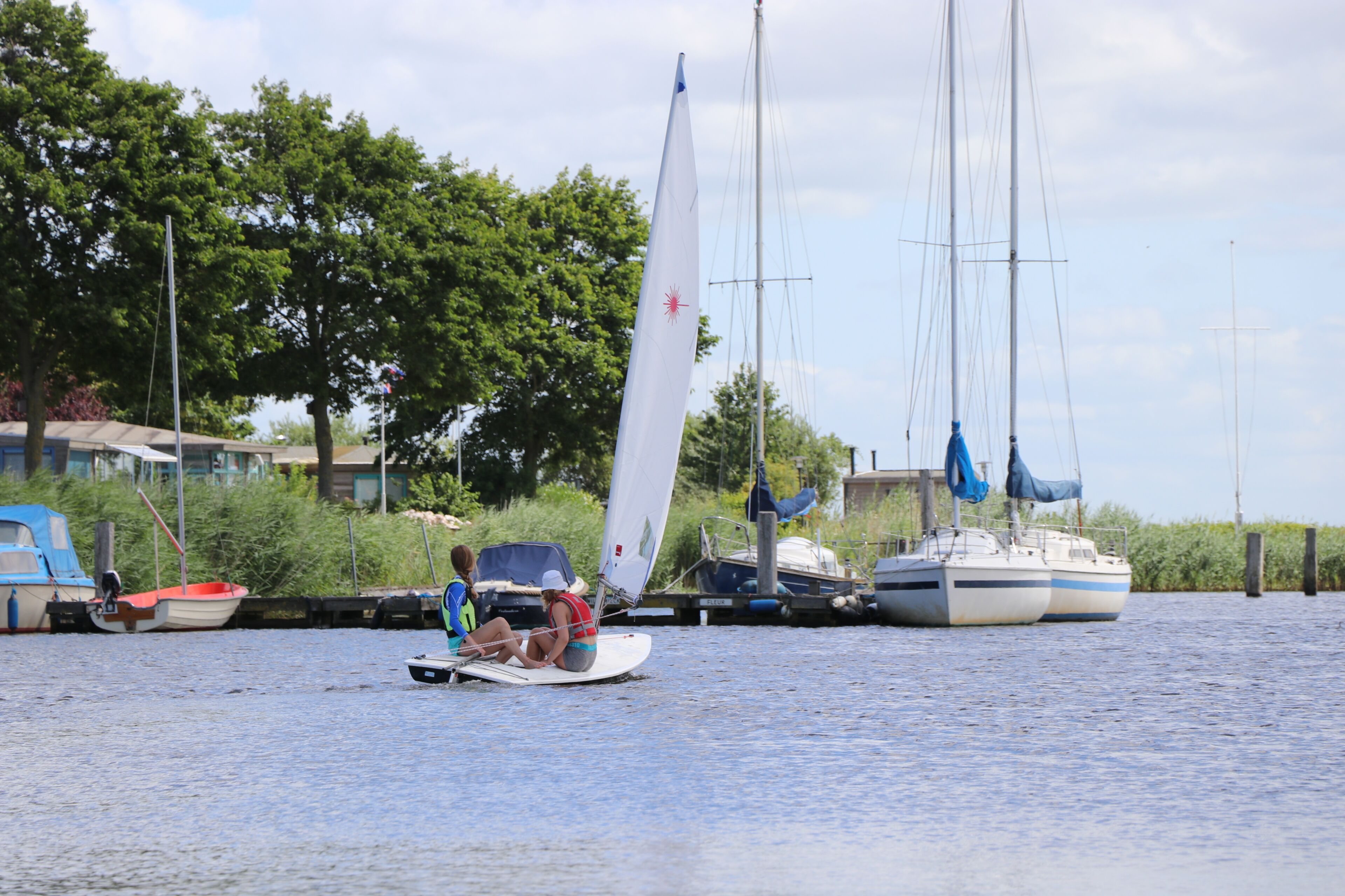 A calm water body with a sailboat and a motorboat.