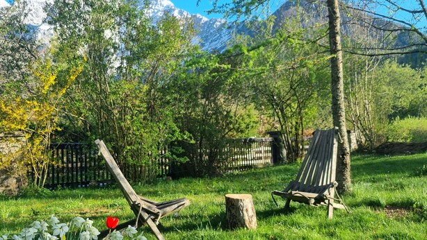 A grassy outdoor area with two wooden chairs, a wooden stump, and a fence. - Vila Zora | Studio apartment | Jezersko (Zgornje Jezersko)