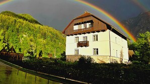 A two-story building with a balcony, surrounded by lush greenery and mountains. - Vila Zora | Studio apartment | Jezersko (Zgornje Jezersko)