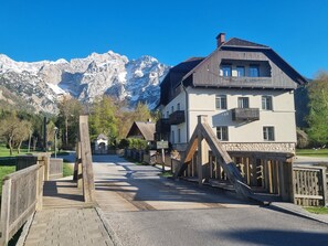 Hotel con vista sulle montagne, dotato di terrazza in legno, pareti in pietra e con le montagne sullo sfondo.