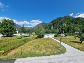 Un sentiero lastricato che si snoda attraverso un'area verdeggiante con alberi e una montagna sullo sfondo.