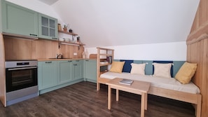 Una cucina funzionale con forno integrato, un tavolo da pranzo in legno e un divano con cuscini.